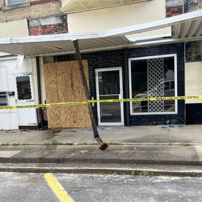 Damage, including a boarded-up storefront and damaged awning supports, is visible on Monroe Street on the south side of the Scotland County Courthouse square in Memphis after authorities said a vehicle struck the building June 6. Branden Lee Hager is charged in Scotland County case No. 26SE-CR00027 with felony leaving the scene of an accident involving property damage exceeding $1,000 and related offenses.